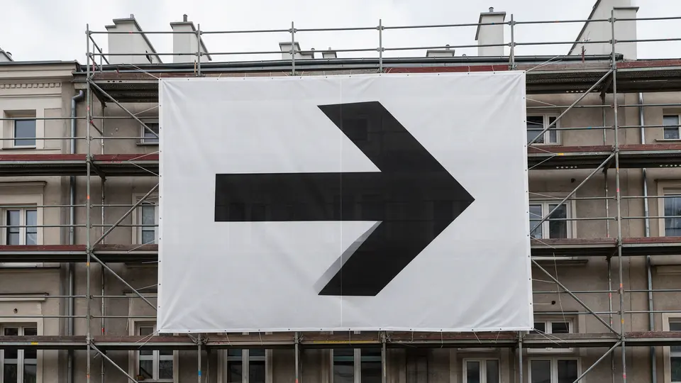 Baner siatkowy z nadrukiem zawieszony na rusztowaniu przy elewacji budynku